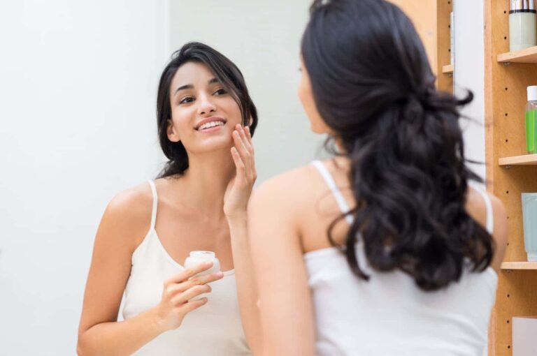 A woman applies skin moisturizer to her face as part of her 15-minute morning routine to get ready efficiently.