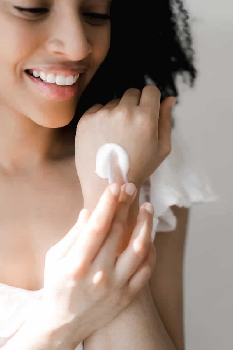 A woman applies white cream to her hand as part of her daily skincare routine.