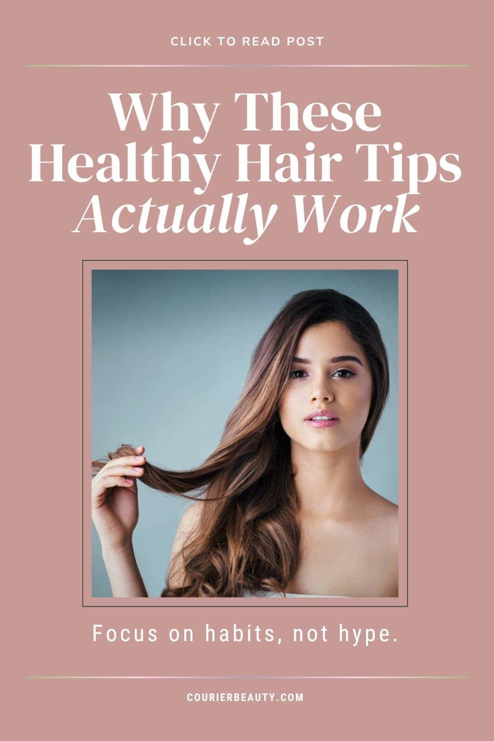 A woman with long, wavy hair touches a strand of her hair.