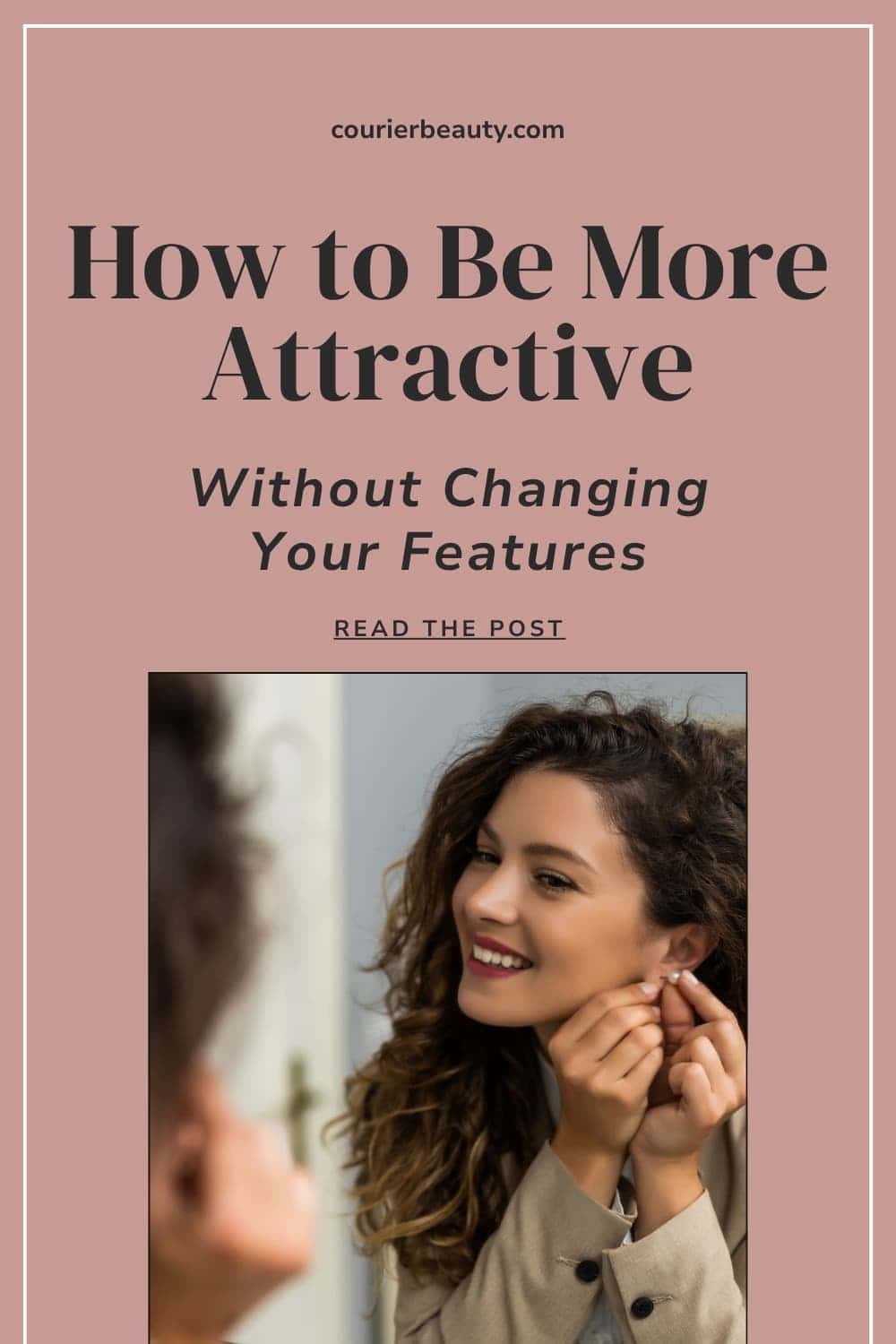 Smiling woman with curly hair wearing a beige coat and putting on earrings in front of a mirror.