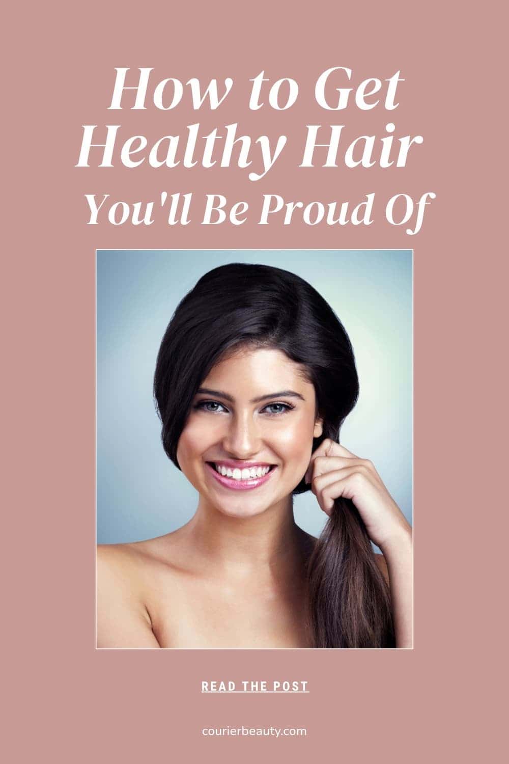 Close-up portrait of a woman with long hair smiling while touching her hair.